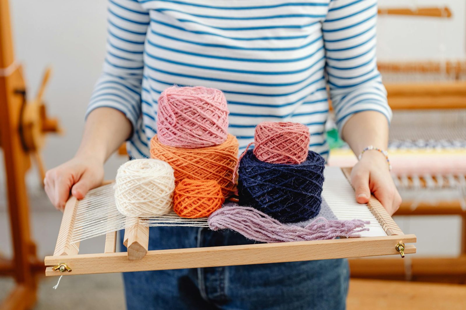 woman holding a weaving loom and yarn
